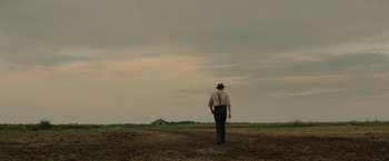 Movie still from “Mudbound” (2017), directed by Dee Rees – A man walking across a dry grass covered field; Extreme Wide shot, Low angle