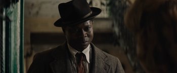 Movie still from “Mudbound” (2017), directed by Dee Rees – A man wearing a suit and a hat is posing for a picture; Close Up shot, Over the shoulder angle