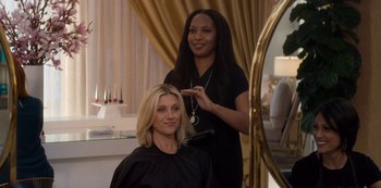 Movie still from “Murder Mystery” (2019), directed by Kyle Newacheck – A woman in a black shirt is getting her hair cut; Medium shot, Over the shoulder angle