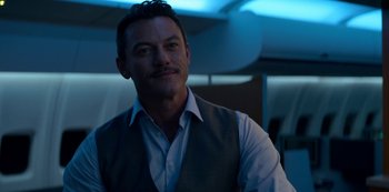 Movie still from “Murder Mystery” (2019), directed by Kyle Newacheck – A person wearing a shirt and vest; Close Up shot, Over the shoulder angle