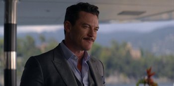 Movie still from “Murder Mystery” (2019), directed by Kyle Newacheck – A person wearing a suit and tie; Close Up shot, Over the shoulder angle