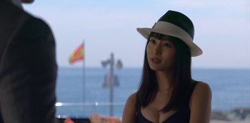 Movie still from “Murder Mystery” (2019), directed by Kyle Newacheck – A woman wearing a hat standing in front of the ocean; Close Up shot, Over the shoulder angle