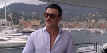 Movie still from “Murder Mystery” (2019), directed by Kyle Newacheck – A person wearing a shirt and sunglasses; Medium shot, Over the shoulder angle