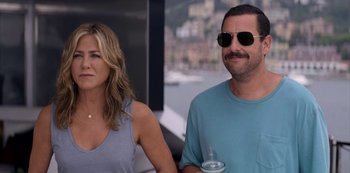 Movie still from “Murder Mystery” (2019), directed by Kyle Newacheck – A man and a woman wearing sunglasses next to each other; Close Up shot, Over the shoulder angle