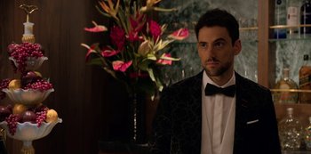Movie still from “Murder Mystery” (2019), directed by Kyle Newacheck – A man in a suit and bow tie next to flowers; Close Up shot, Over the shoulder angle