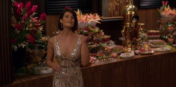 Movie still from “Murder Mystery” (2019), directed by Kyle Newacheck – A woman standing in front of a buffet holding a glass of wine; Medium shot, Over the shoulder angle