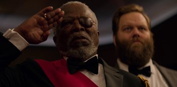 Movie still from “Murder Mystery” (2019), directed by Kyle Newacheck – An older man in a suit and tie with one eye open; Close Up shot, Low angle