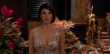 Movie still from “Murder Mystery” (2019), directed by Kyle Newacheck – A woman in a silver dress standing in front of flowers; Close Up shot, Over the shoulder angle