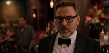 Movie still from “Murder Mystery” (2019), directed by Kyle Newacheck – A person wearing a suit and bow tie; Close Up shot, Over the shoulder angle