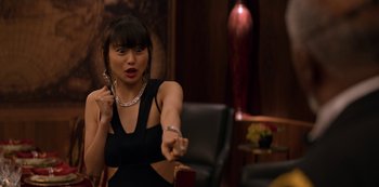Movie still from “Murder Mystery” (2019), directed by Kyle Newacheck – A woman in a black dress is pointing at something; Medium shot, Over the shoulder angle