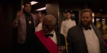 Movie still from “Murder Mystery” (2019), directed by Kyle Newacheck – A group of men in suits and ties standing in a room; Medium shot, Over the shoulder angle