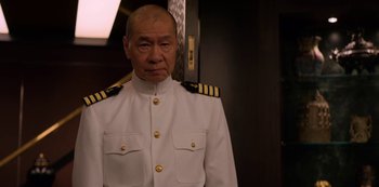 Movie still from “Murder Mystery” (2019), directed by Kyle Newacheck – A man in a uniform standing in front of a door; Medium shot, Low angle