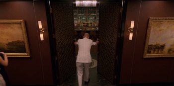 Movie still from “Murder Mystery” (2019), directed by Kyle Newacheck – A man in a white suit standing in a room; Wide shot, Low angle