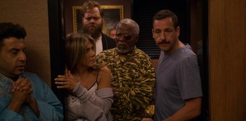 Movie still from “Murder Mystery” (2019), directed by Kyle Newacheck – A group of people standing next to each other in a room; Medium shot, High angle