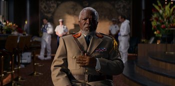 Movie still from “Murder Mystery” (2019), directed by Kyle Newacheck – An older man in a military uniform is posing for a picture; Medium shot, Low angle