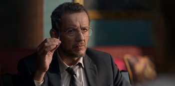 Movie still from “Murder Mystery” (2019), directed by Kyle Newacheck – A person wearing a suit and glasses; Close Up shot, Over the shoulder angle