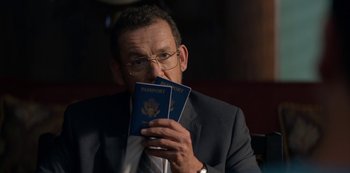 Movie still from “Murder Mystery” (2019), directed by Kyle Newacheck – A man in a suit holding two passports in his hands; Close Up shot, Over the shoulder angle