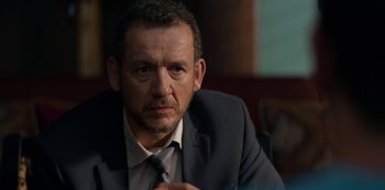 Movie still from “Murder Mystery” (2019), directed by Kyle Newacheck – A person wearing a suit and tie; Close Up shot, Over the shoulder angle