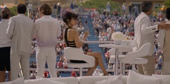 Movie still from “Murder Mystery” (2019), directed by Kyle Newacheck – A woman sitting on a chair holding a cell phone; Wide shot, Over the shoulder angle