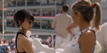 Movie still from “Murder Mystery” (2019), directed by Kyle Newacheck – Two women are sitting in chairs and one is wearing sunglasses; Medium shot, Over the shoulder angle