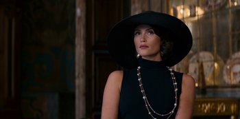 Movie still from “Murder Mystery” (2019), directed by Kyle Newacheck – A woman in a black dress and a black hat; Close Up shot, Over the shoulder angle