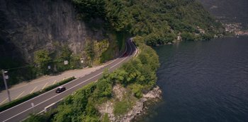 Movie still from “Murder Mystery” (2019), directed by Kyle Newacheck – An aerial view of a road next to a body of water; Extreme Wide shot, High angle
