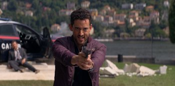 Movie still from “Murder Mystery” (2019), directed by Kyle Newacheck – A man holding a gun in his hand; Medium shot, Over the shoulder angle