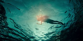Movie still from “Mute” (2018), directed by Duncan Jones – A person swimming in a body of water; Wide shot, Overhead angle