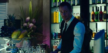 Movie still from “Mute” (2018), directed by Duncan Jones – A man standing at a bar in front of some glasses; Medium shot, Over the shoulder angle