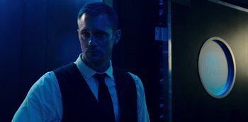 Movie still from “Mute” (2018), directed by Duncan Jones – A man wearing a vest and tie in a dark room; Close Up shot, Low angle