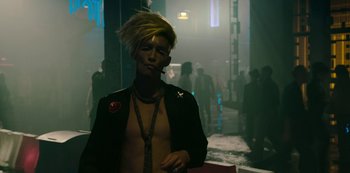 Movie still from “Mute” (2018), directed by Duncan Jones – A man smoking a cigarette while wearing a jacket; Medium shot, Over the shoulder angle