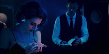 Movie still from “Mute” (2018), directed by Duncan Jones – A man and a woman in a dark room; Medium shot, Over the shoulder angle