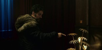 A man pointing to a plant that is growing