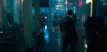 Movie still from “Mute” (2018), directed by Duncan Jones – A man is walking down the street in the rain; Wide shot, Over the shoulder angle