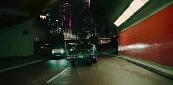 Movie still from “Mute” (2018), directed by Duncan Jones – A car driving down a street at night; Wide shot, High angle