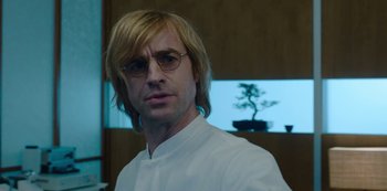 Movie still from “Mute” (2018), directed by Duncan Jones – A man with long blonde hair wearing glasses; Close Up shot, Over the shoulder angle