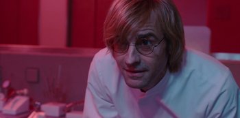 Movie still from “Mute” (2018), directed by Duncan Jones – A person wearing glasses and a white shirt; Close Up shot, Low angle