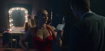 Movie still from “Mute” (2018), directed by Duncan Jones – A woman in a red dress looking at a piece of paper; Medium shot, Over the shoulder angle