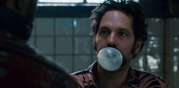 Movie still from “Mute” (2018), directed by Duncan Jones – A man blowing a bubble with a chewing gum bubble in his mouth; Close Up shot, Over the shoulder angle