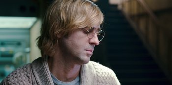 Movie still from “Mute” (2018), directed by Duncan Jones – A person wearing glasses and a sweater; Close Up shot, Over the shoulder angle
