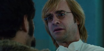Movie still from “Mute” (2018), directed by Duncan Jones – A person wearing glasses and a beard; Close Up shot, Over the shoulder angle