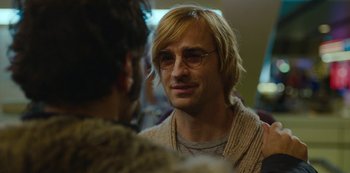 Movie still from “Mute” (2018), directed by Duncan Jones – A person wearing glasses and a sweater; Close Up shot, Over the shoulder angle