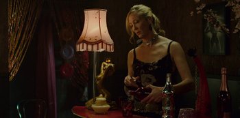 Movie still from “Mute” (2018), directed by Duncan Jones – A beautiful woman standing in front of a table with a lamp; Medium shot, Over the shoulder angle
