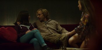 Movie still from “Mute” (2018), directed by Duncan Jones – A man and a woman sitting on a red couch; Medium shot, Over the shoulder angle