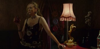 Movie still from “Mute” (2018), directed by Duncan Jones – A woman standing next to a table with a lamp on top of it; Medium shot, Over the shoulder angle