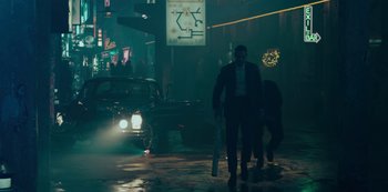 Movie still from “Mute” (2018), directed by Duncan Jones – A man walking down the street at night; Wide shot, Over the shoulder angle