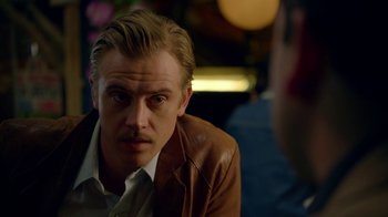 Movie still from “Narcos” (2015), created by Chris Brancato – A person wearing a leather jacket; Close Up shot, Over the shoulder angle