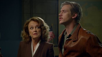 Movie still from “Narcos” (2015), created by Chris Brancato – A woman and a man standing next to each other; Medium shot, Over the shoulder angle