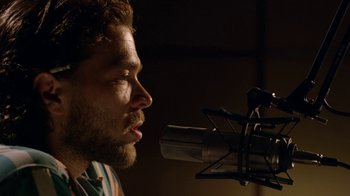 Movie still from “Narcos” (2015), created by Chris Brancato – A person with a microphone; Close Up shot, Low angle