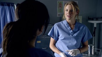 Movie still from “Narcos” (2015), created by Chris Brancato – A woman in a blue lab coat talking to another woman in a blue lab coat; Close Up shot, Over the shoulder angle